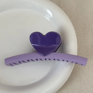 Detail view of a purple heart claw clip with a two-tone acrylic finish on a white plate