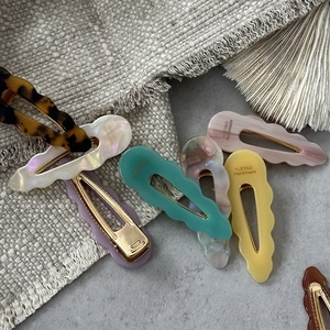 Detail showing wavy acetate hair clips in various marble patterns with metal clips