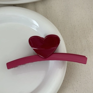Detailed view of the glossy heart-shaped hair claw clip on a white ceramic plate