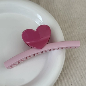 Close-up of heart-shaped hair claw clip in deep pink and light pink resin finish