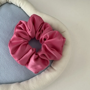 Detail of dark pink satin scrunchie with smooth texture in a light blue jewelry tray