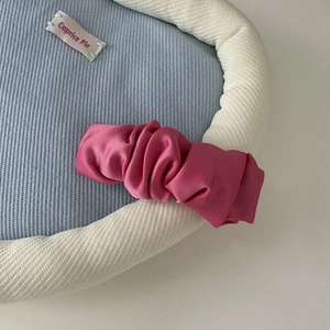 Detailed view of rose pink satin scrunchie featuring smooth silk-like texture and elegant folds