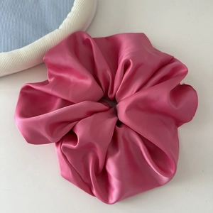Close-up of pink oversized satin scrunchie with silky texture and elegant folds