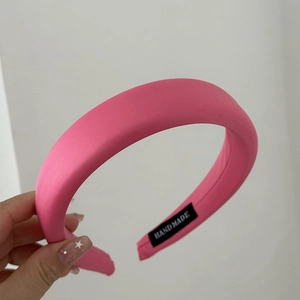 Macro view of hot pink satin headband with handmade label and high-quality fabric texture
