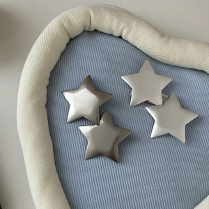 Detailed close-up of four matte silver star-shaped metal hair clips on a soft blue cushion