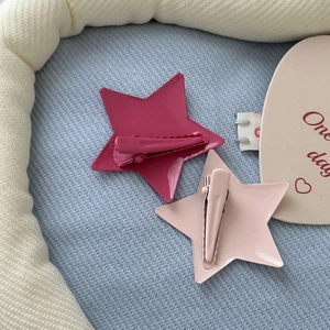 Detail of star-shaped Y2K hair clips in pink matte alloy with secure metal duckbill grips
