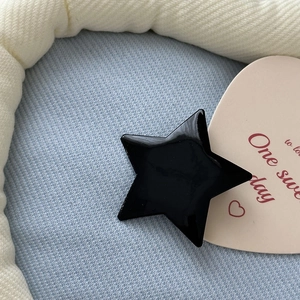 Macro view of a shiny black star hair clip with metallic finish on soft aesthetic props