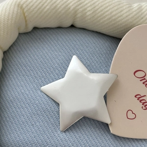 Detailed macro view of matte silver star hair clip on soft light blue knit fabric