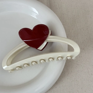 Detailed close-up of cream-colored heart hair claw clip with dark red heart decor