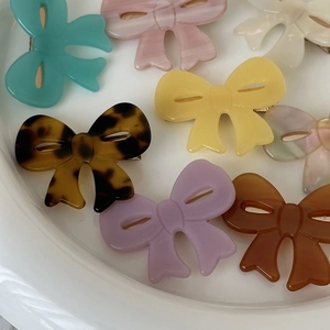 Detailed view of colorful acetate bow hair clips in mint, pink, and leopard print patterns