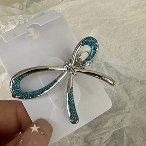 Détail de la pince à cheveux noeud argenté avec émail bleu sur carte de présentation