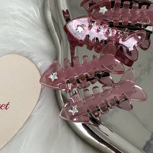 Detail of pink Y2K fishbone hair clip with silver star on a reflective mirror tray