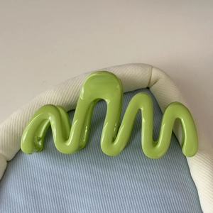Vue détaillée de la pince à cheveux ondulée vert vif avec une finition brillante moderne