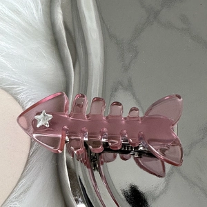 Detailed macro view of pink translucent fishbone hair clip with silver star rhinestone