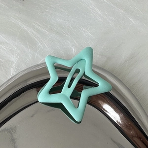 Detailaufnahme einer Y2K mintgrünen Haarspange in Sternform mit mattem Finish auf Kunstfell