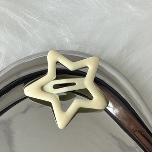 Detailansicht einer matten creme-sternförmigen Metallhaarklammer auf Plüschhintergrund