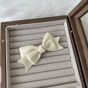 Close-up of cream grosgrain ribbon bow hair clip in a wooden jewelry box