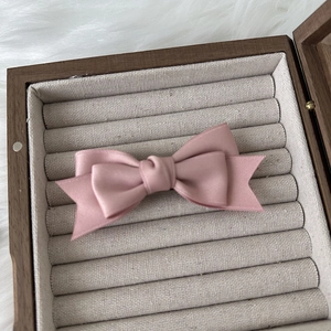 Close-up of pink layered bow hair clip with silk texture in a velvet jewelry box