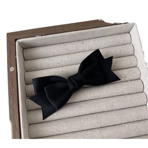 Elegant double-layered black satin bow hair clip displayed in a wooden jewelry box