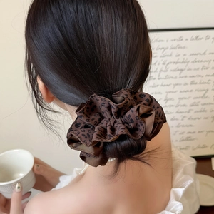 Chouchou imprimé léopard marron foncé porté sur un chignon bas pour femme élégante