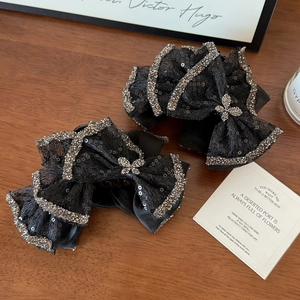 Close-up of black lace bow hair clips with shimmering sequins and crystal-encrusted edges
