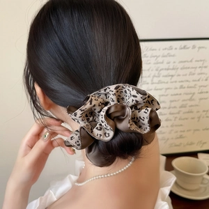 Chouchou imprimé léopard marron pour femme présenté sur un chignon de queue de cheval