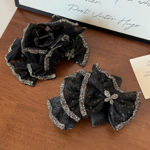 Elegant black lace hair claw clips with sparkling rhinestone bows on dark wooden surface