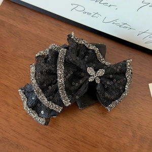 Detail of black mesh hair claw with sparkling sequins and silver rhinestone butterfly