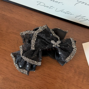Close-up of black mesh bow hair claw with sparkling silver sequins and butterfly rhinestone