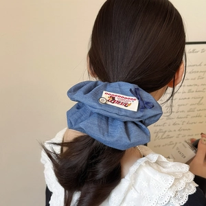 Blue denim scrunchie with button and ribbon detail on a girl's ponytail