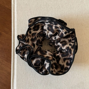Detail of leopard print hair scrunchie with black wavy edges on a minimalist background