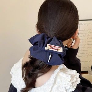 Detail of navy blue fabric scrunchie with handmade label and button on ponytail