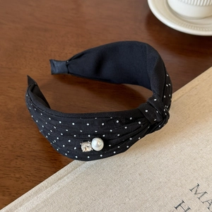 Close-up of knotted polka dot headband featuring elegant pearl and rhinestone accents