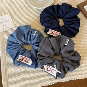 Detailed view of three denim fabric scrunchies with handmade labels and cute bow accents