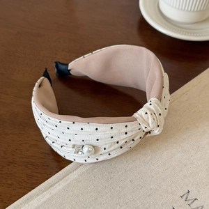 Close-up of knotted polka dot headband with faux pearl and crystal accent on wooden table