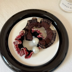 Detail of plaid scrunchies with faux pearls in a minimalist ceramic dish setting
