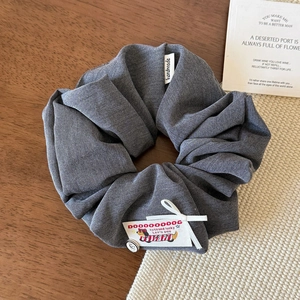 Detail of dark grey denim scrunchie with handmade label and smile button decoration