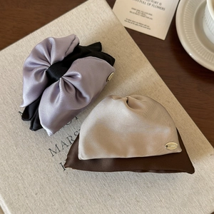 Close-up of satin bow hair clips with Lucky metal logo on textured book cover background