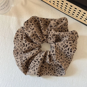 Detailed view of large leopard print scrunchie with vintage fabric texture on white cloth