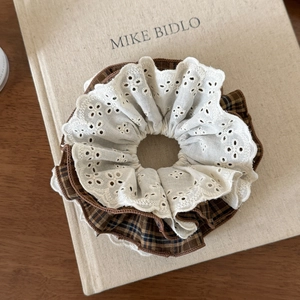 Détail d'un chouchou double couche avec dentelle blanche et tissu à carreaux marron