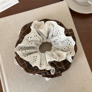 Détail du chouchou à carreaux marron avec dentelle sur une surface en lin rustique