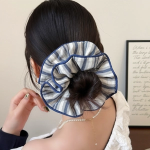 Blue and white striped fabric scrunchie with dark blue edging worn by a model