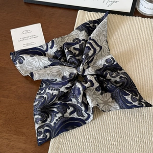 Elegant oversized silk square scarf with blue baroque totem prints on a wooden surface