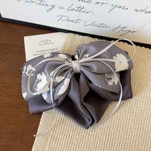 Détail de la pince à cheveux en satin gris foncé avec imprimé floral et ruban argenté