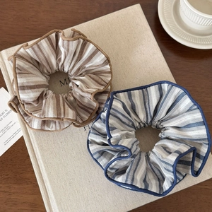 Chic blue and brown striped fabric scrunchies on a book with a cozy aesthetic setup