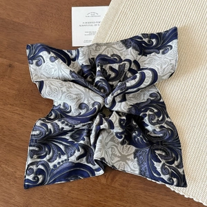 Detailed view of elegant blue and white baroque silk scarf on a wooden texture background