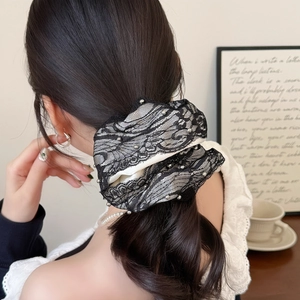 Detail of beaded lace scrunchie with white fabric and black trim on low ponytail