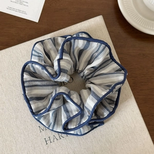 Detail of blue striped fabric scrunchie with navy piping on a minimalist book cover