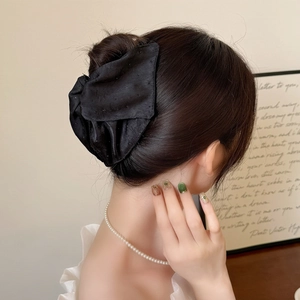 Pince à cheveux triangle en tissu noir élégant portée sur un chignon pour un style chic