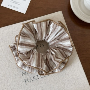 Close-up of brown and white striped fabric scrunchie with detailed stitching and soft pleats